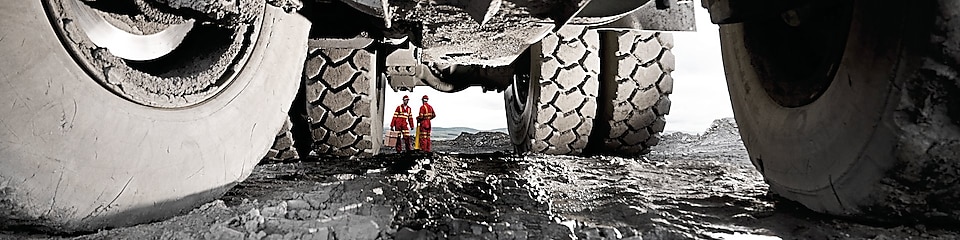 Two men standing behind a huge truck