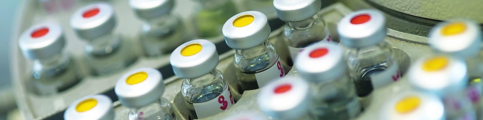 Rows of medicine vials sitting in a holder, some with red dots on the lid, and some with yellow dots on the lid