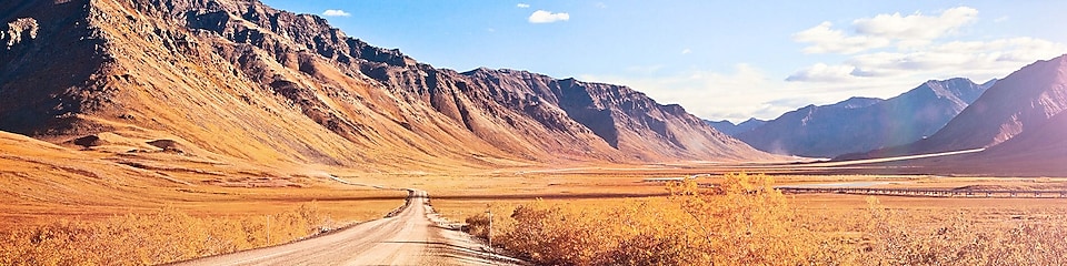 Empty dirt road surrounded by mountains