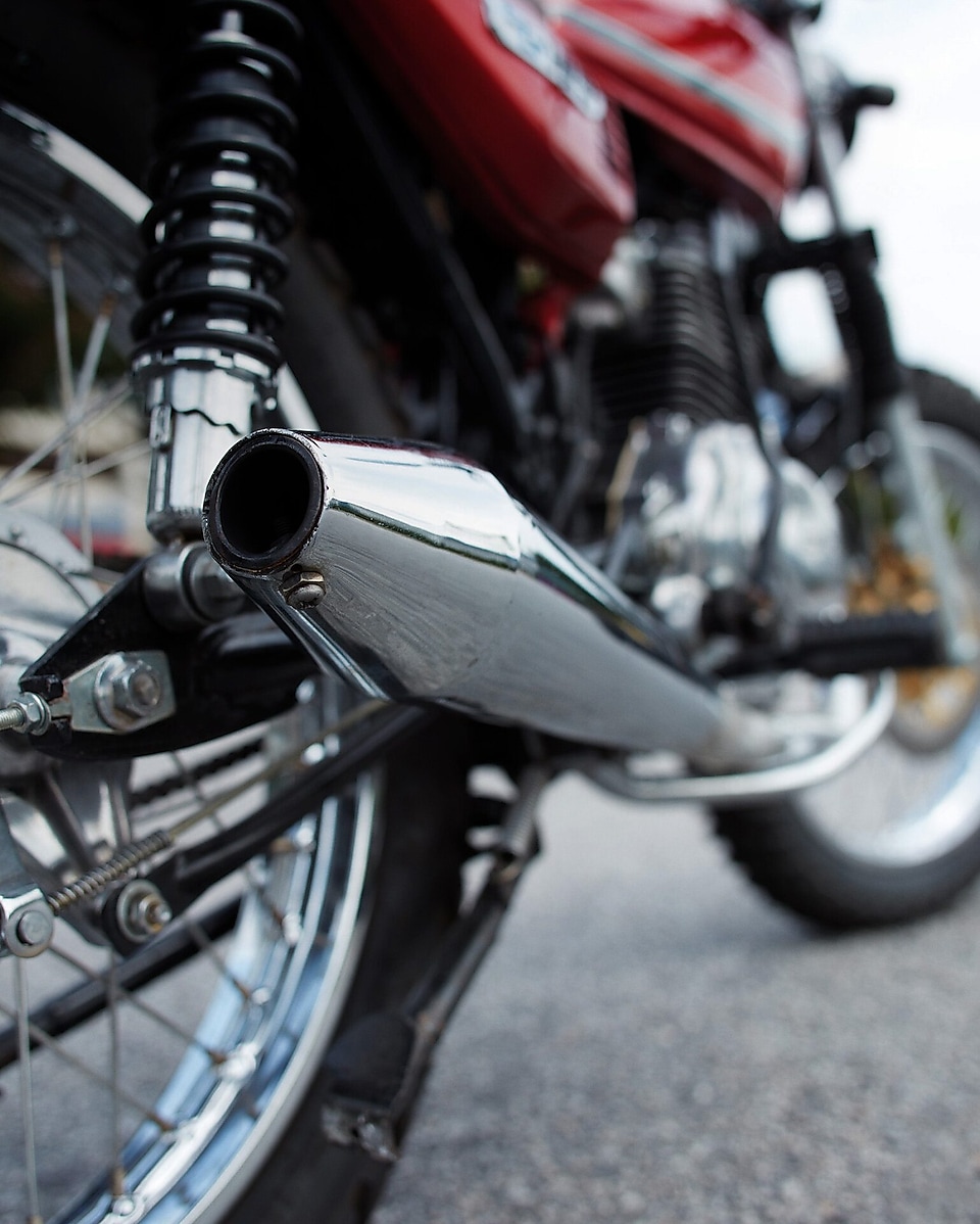 Red motorcycle and rider on a road with cars and buildings in the background