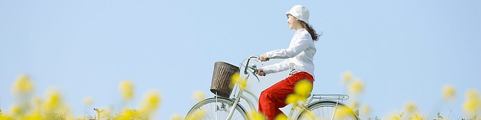 Seorang gadis mengendarai sepeda melintasi ladang di musim panas