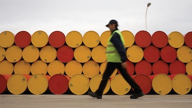 pria menggelindingkan barel pelumas