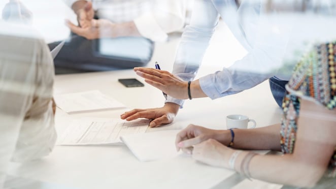 Hands and documents seen in business meeting in conference room behind glass wall