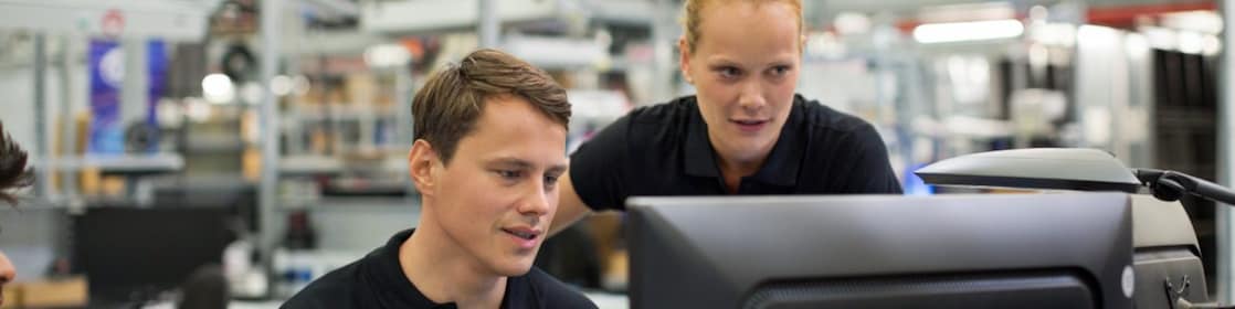 Male and female employees using desktop computer in logistics warehouse