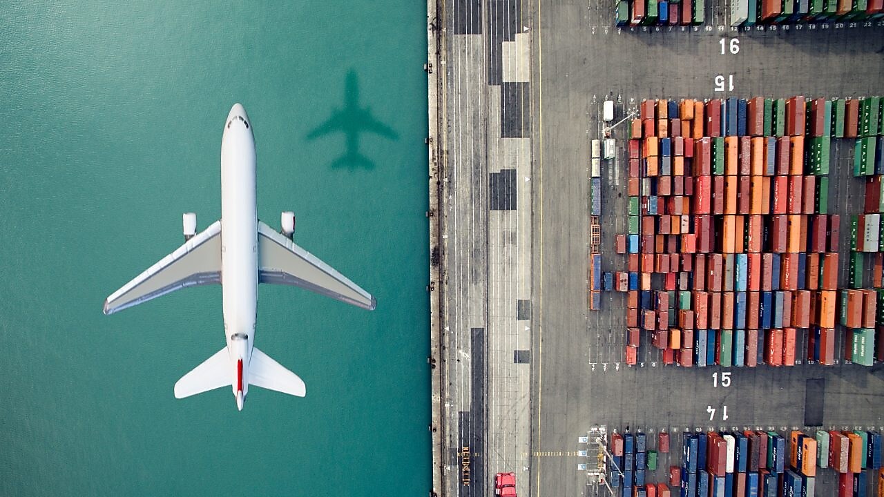 Airplane flying over container port