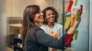 Two women writing on notice board