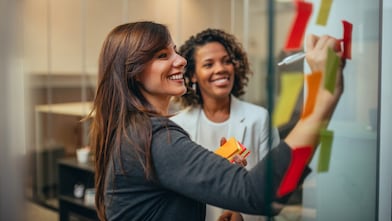 Two women writing on notice board