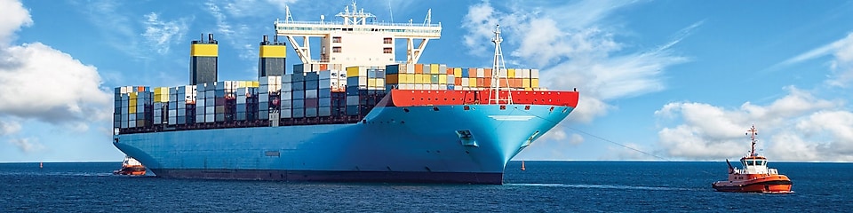 Large cargo vessel being pulled by tugboat