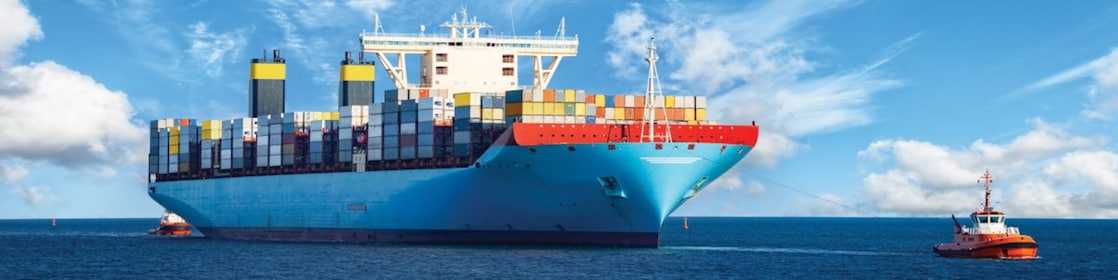 Large cargo vessel being pulled by tugboat