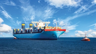 Large cargo vessel being pulled by tugboat