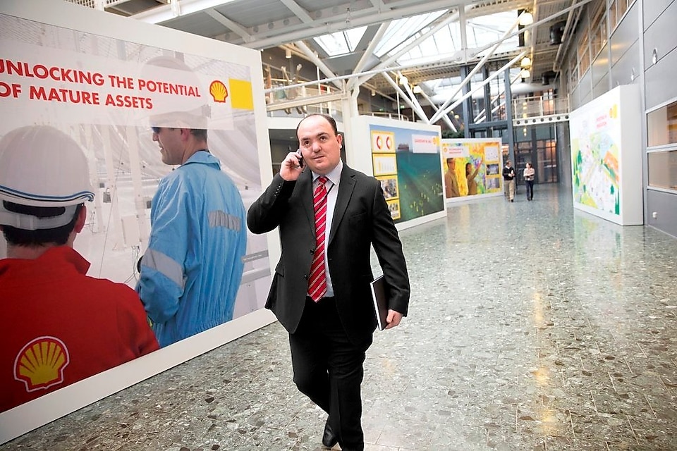 Andy Kneen berjalan dan berbicara melalui telepon di kantor Shell