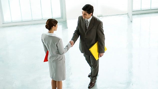 Pebisnis pria dan wanita berjabat tangan di lobi