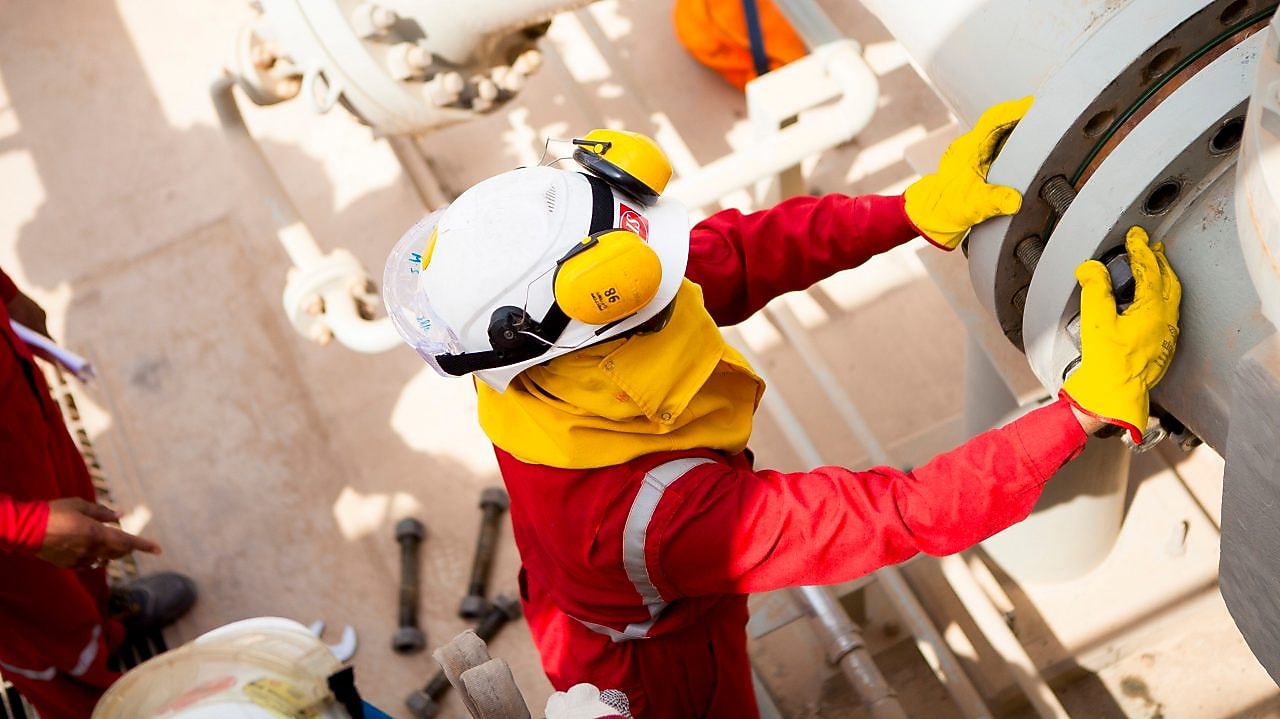 Pekerja mengenakan masker pelindung dan sarung tangan