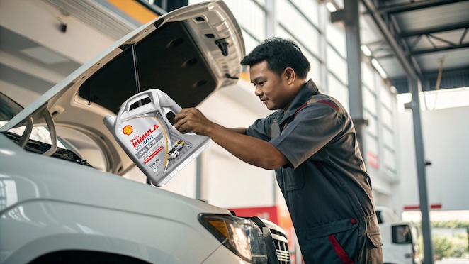 Mekanik sedang memeriksa pelumas truk.