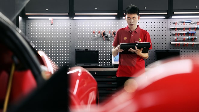 Seorang mekanik di bengkel sedang melakukan pemeriksaan pada mobil.