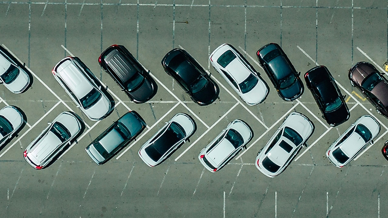 Deretan mobil di parkiran dan salah satunya terparkir miring dengan roda depan berbelok tajam.