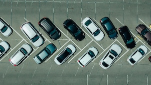 Deretan mobil di parkiran dan salah satunya terparkir miring dengan roda depan berbelok tajam.