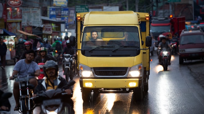 Truk sedang melaju di jalan perkotaan.