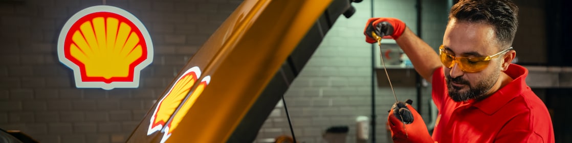 Seseorang sedang mengecek oli mesin mobil secara mandiri.