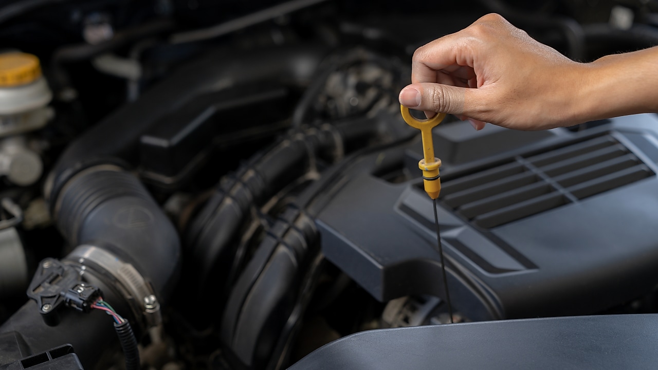 Seseorang sedang menggunakan dipstick untuk memeriksa level oli.