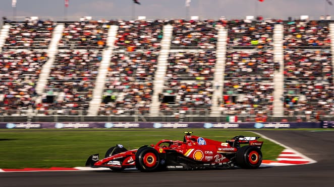 Mobil balap Ferrari sedang melaju di sirkuit Yas Marina di hadapan penonton di tribun.