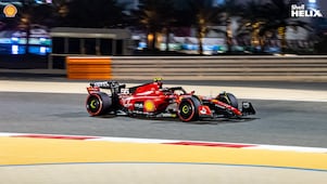 Mobil balap ferrari dengan logo Shell sedang melaju di sirkuit.