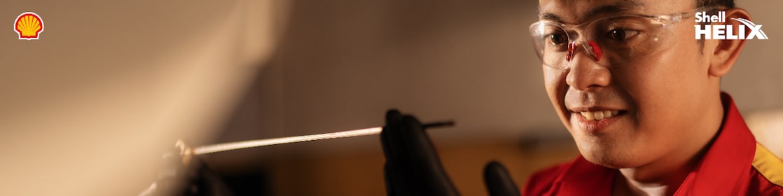 Seorang mekanik Shell sedang melihat dipstick yang digunakan untuk memeriksa kondisi oli mobil.