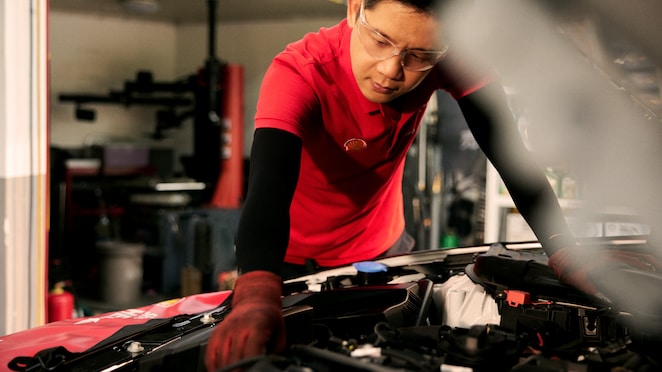 Seorang mekanik Shell sedang memeriksa kondisi komponen mobil.