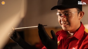 Seorang mekanik Shell sedang melihat dipstick yang digunakan untuk memeriksa kondisi oli mobil.