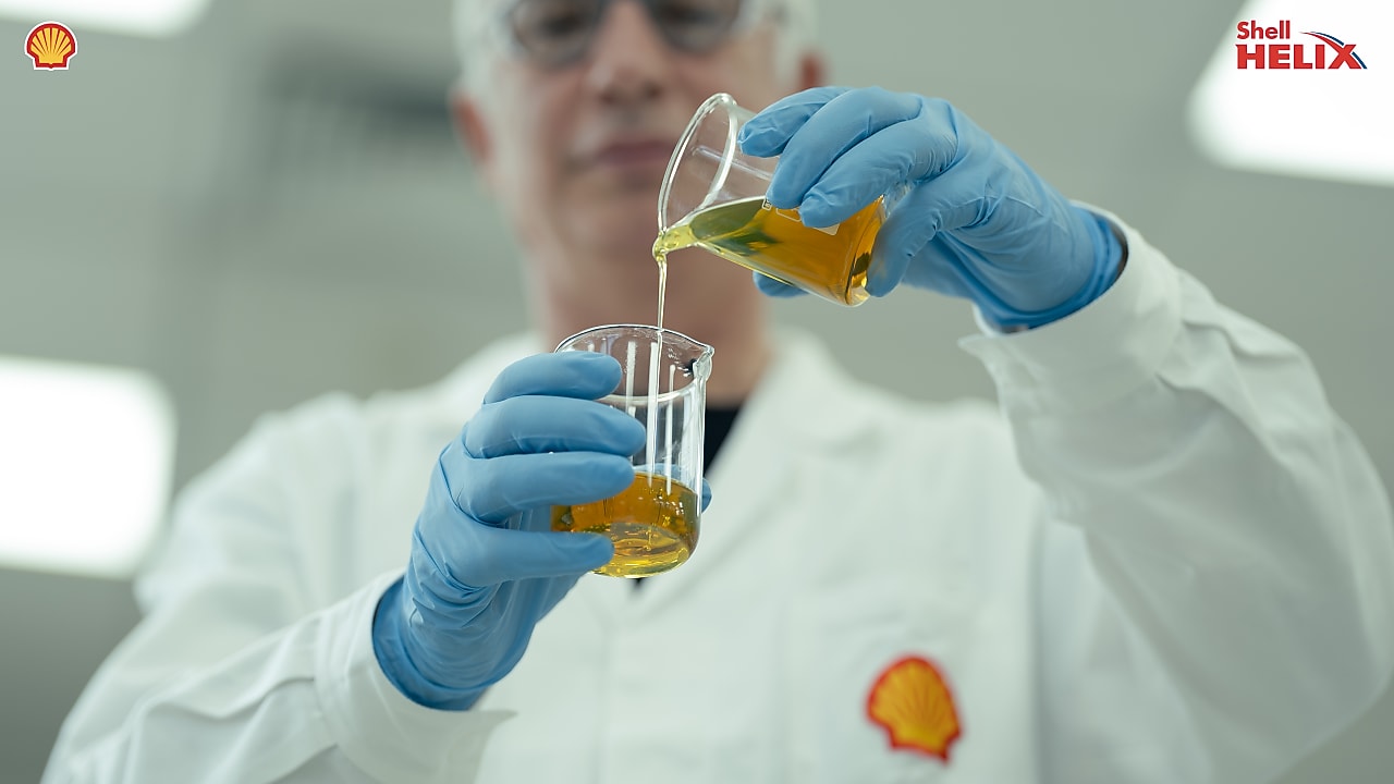 seorang pria menuangkan minyak ke dalam labu kaca