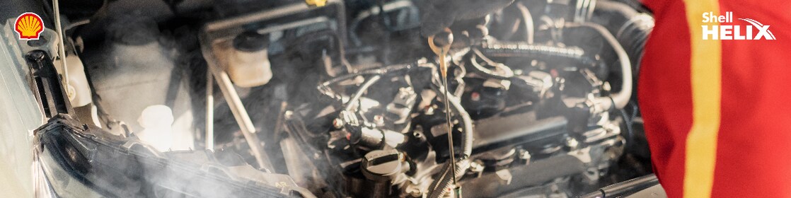 Mekanik Shell sedang mengecek oli mesin mobil.