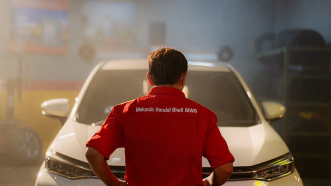 Seorang mekanik Shell BIWS hendak memeriksa mobil di bengkel, siap mengatasi masalah overheat.