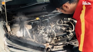 Mekanik Shell sedang mengecek oli mesin mobil.