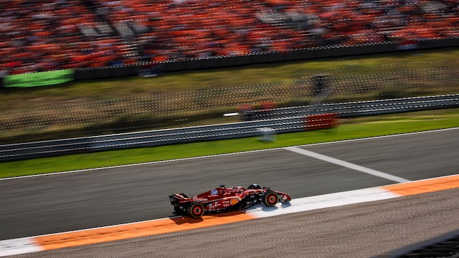 Mobil balap sedang melaju kencang di sirkuit.