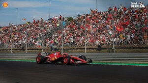 Mobil balap ferrari dengan logo Shell sedang melaju di sirkuit.