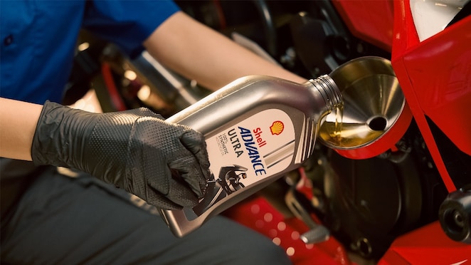 Proses ganti pelumas pada sepeda motor oleh mekanik.
