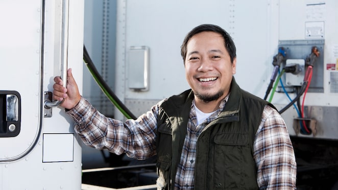 Potret seorang sopir truk bersama sebuah truk besar.