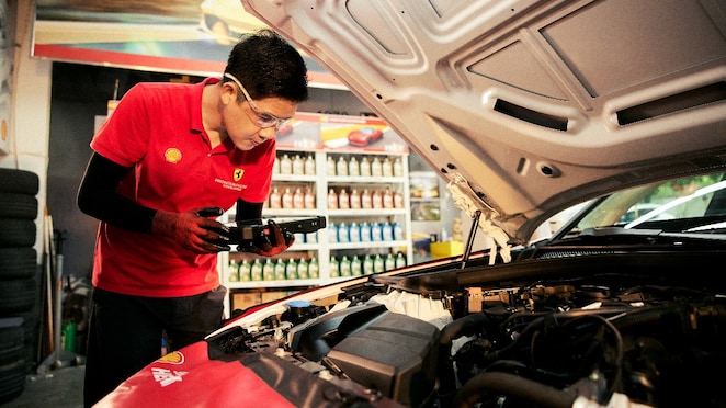Teknisi bengkel sedang melakukan pengecekan rutin mobil.