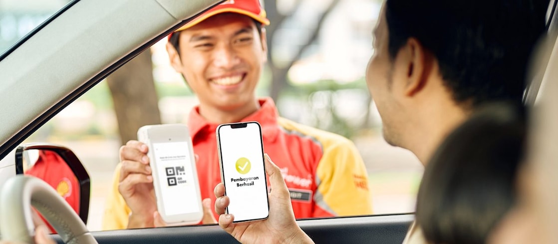Woman giving card from car window at petrol station