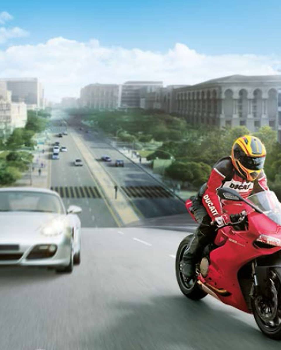 Pengendara sepeda motor merah di jalan dengan latar belakang mobil dan gedung
