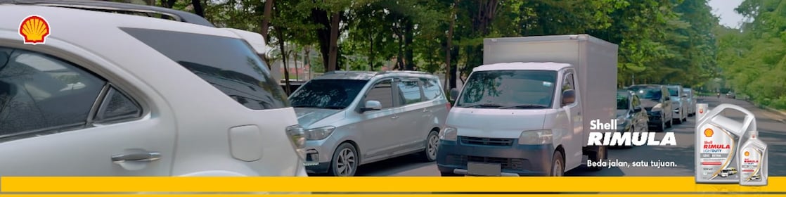 Truk dan mobil melaju di jalan perkotaan bersama Shell Rimula LD4  Extra, menampilkan produk dan logo Shell.