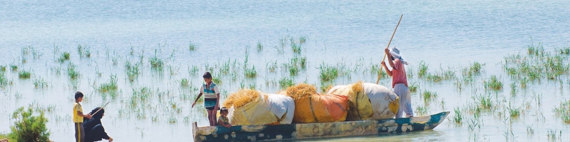 Penduduk lokal menyeberangi Rawa Hawizeh yang tergenang banjir, di dekat proyek Majnoon di Irak